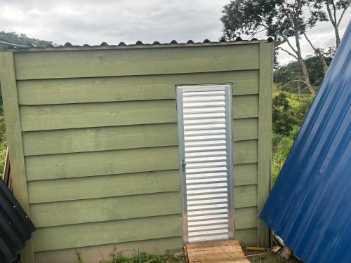 a small green shed with a door in it at Bangalô Cachoeira Bem Vinda in Itabirito