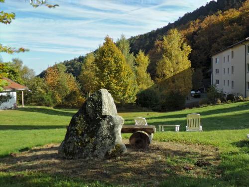 a stone bench and two chairs in a park at Hotel-Spa & Restaurant Logis Domaine Langmatt in Murbach