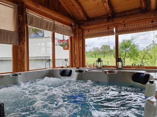 a bath tub filled with water in front of windows at Holiday home Poljak in Tounj