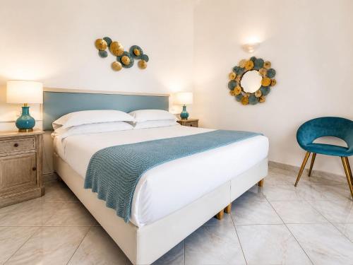 a bedroom with a large bed and a blue chair at Hotel Guarracino in Capri