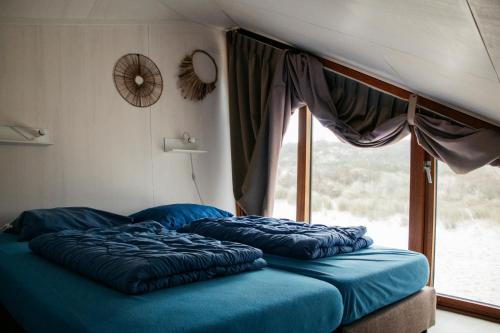 two beds in a room with a window at Breezand Beachhouses in Vrouwenpolder