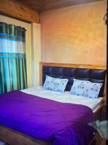 a bedroom with a bed with purple sheets and pillows at Jakhu heights B&B in Shimla