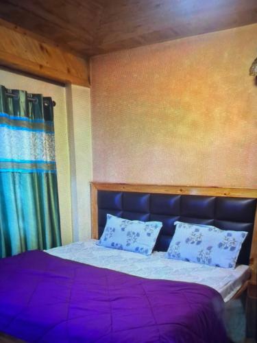 a bedroom with a bed with purple sheets and pillows at Jakhu heights B&B in Shimla