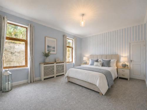 a bedroom with a large bed and two windows at North Lodge - NC500 in Helmsdale