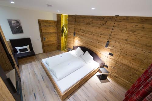 Cama blanca grande en habitación con suelo de madera en Ferienhaus Alpina, en Kals am Großglockner