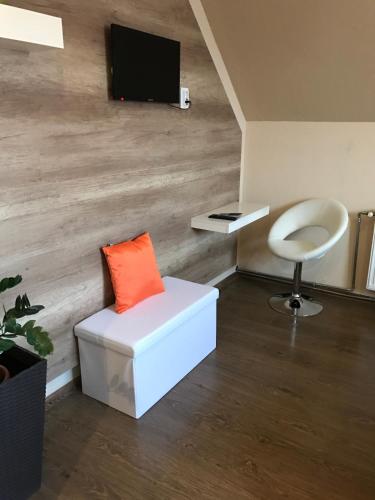 a room with a white chair and a tv on a wall at Abszolút Hotel és Panzió in Nyírbátor