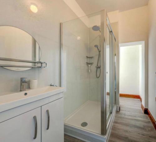 a white bathroom with a shower and a sink at North Lodge - NC500 in Helmsdale