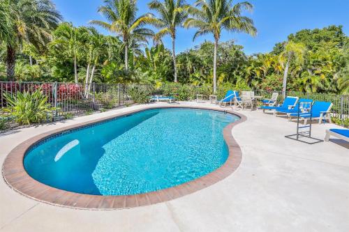 a swimming pool with blue chairs and palm trees at Royal Palm House in Captiva