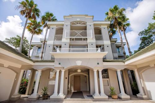 a large white mansion with palm trees at Ibis At The Sanctuary A302 in Sanibel