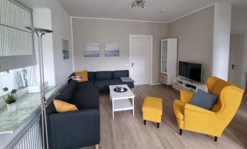 a living room with a blue couch and yellow chairs at Ferienwohnung Biethahn - Gaarden in Groß Brodersby