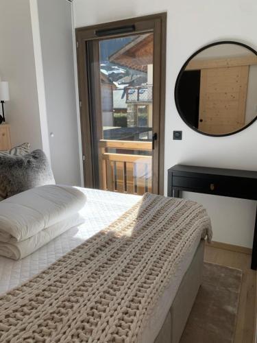 a bedroom with a large bed and a mirror at Dents Blanches B103 by Avecoeur in Morzine
