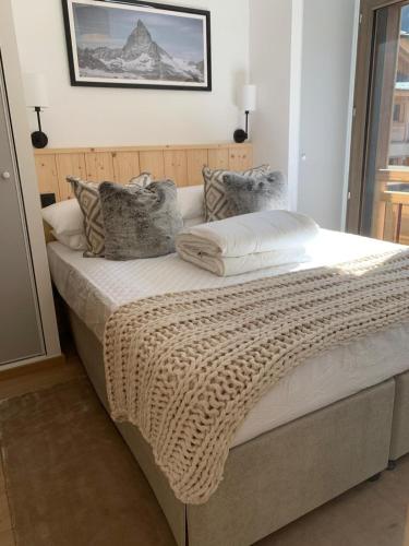 a bed with a blanket and pillows on it at Dents Blanches B103 by Avecoeur in Morzine