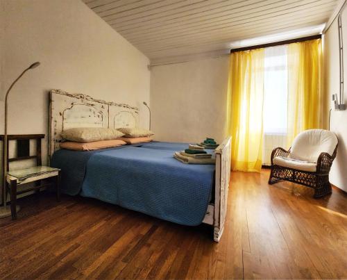 a bedroom with a bed and a chair and a window at Villa Coccodrilla Varallese in Varallo