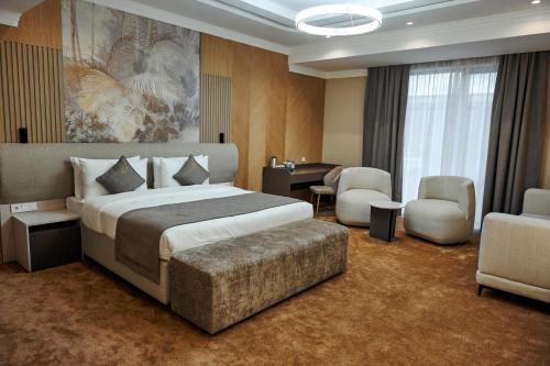 a hotel room with a bed and a desk and chairs at Grand Altyn Hotel in Shymkent