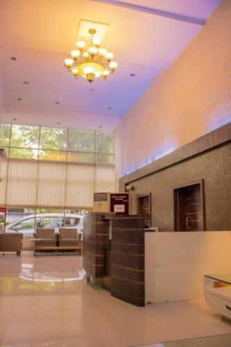 a lobby with a check in counter and a chandelier at Hotel Orchard in Pune