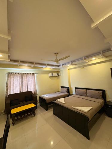 a room with two beds and a couch at Restora Amaze Inn in Bangalore