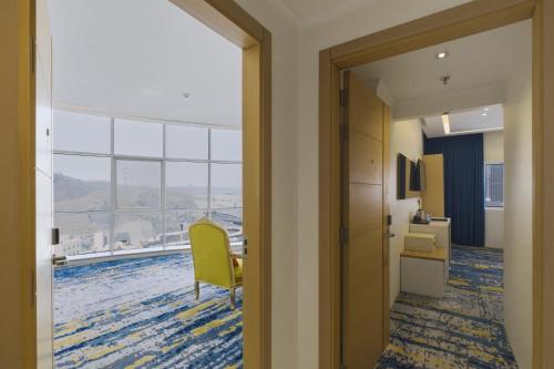 an open door to a room with a table and a yellow chair at Taj Park Hotel in Mecca