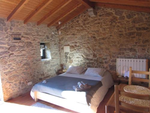 a bedroom with a bed in a stone wall at Casa Rústica, perto do Castelo de Óbidos in Óbidos