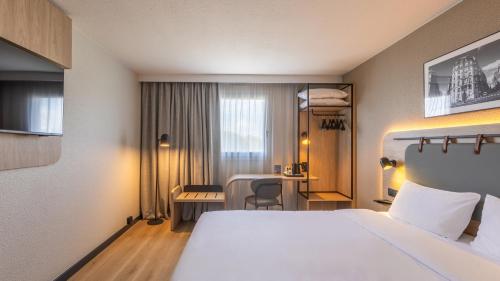 a hotel room with a large bed and a desk at Campanile PRIME - Le Blanc Mesnil in Le Blanc-Mesnil