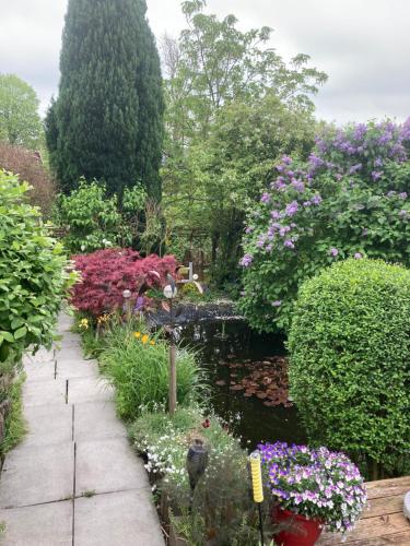 a garden with a pond with flowers and a bird bath at Ferienwohnung am Siel in Ditzum