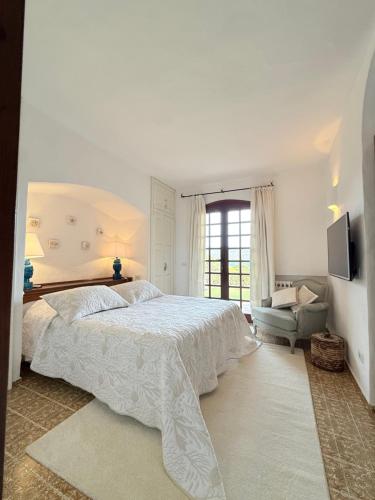 a white bedroom with a large bed and a chair at Villa Annalia in Cannigione