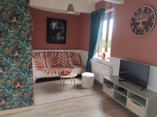a living room with a television and a chair at Le clos du Souffle in Saint-Ouen-sous-Bailly