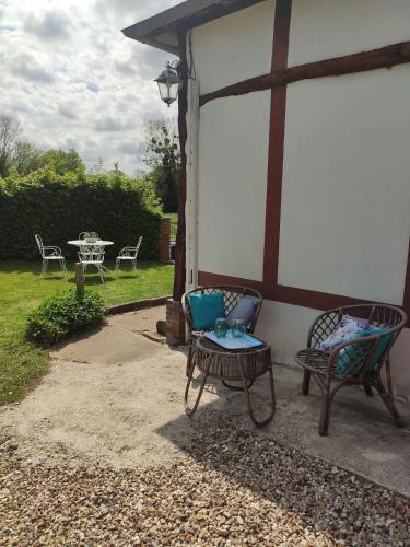 a patio with two chairs and a table and a table and chairs at Le clos du Souffle in Saint-Ouen-sous-Bailly