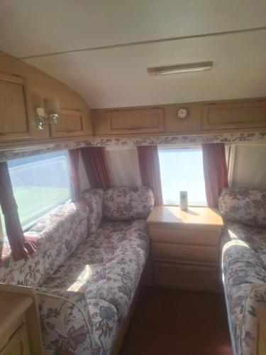 a camper van with a couch and two windows at Park house farm caravan 2 in Richmond