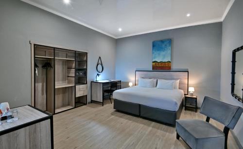 a bedroom with a bed and a desk and a chair at BON Hotel Rustenburg in Rustenburg
