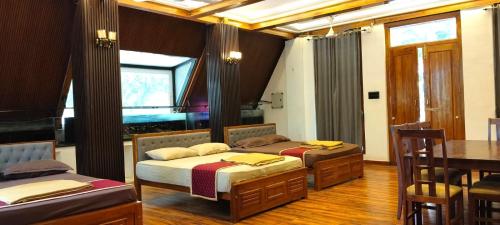 two beds in a room with a table and a dining room at Moonlight Resorts Idappadi in Ammāpettai