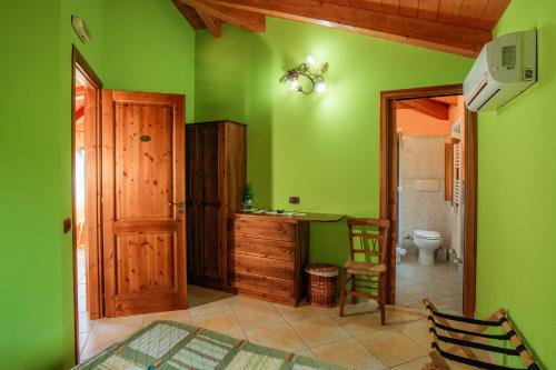 a bedroom with green walls and a bathroom with a toilet at Villa Nigro in Laureana Cilento