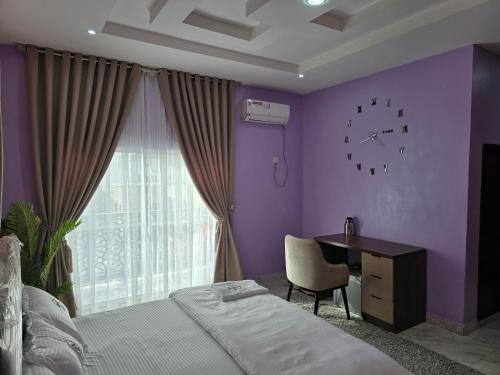 a bedroom with a purple wall with a bed and a desk at House 27 in Idu