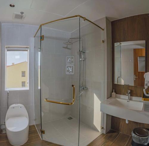 a bathroom with a shower and a toilet and a sink at RosaLie Quảng Bình Hotel in Dong Hoi