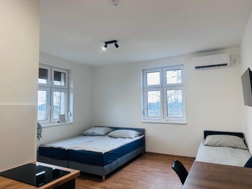 a bedroom with two beds and two windows at Apartamenty przy Galerii in Kluczbork