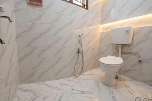 a white bathroom with a toilet and a shower at Kattil Madurai in Madurai