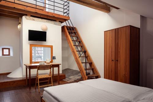 a bedroom with a bed and a desk and a staircase at Zámecký Hotel Litomyšl in Litomyšl