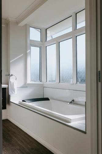 a bathroom with a bath tub in front of a window at Marsden Manor - Spacious house with large pool in Greymouth