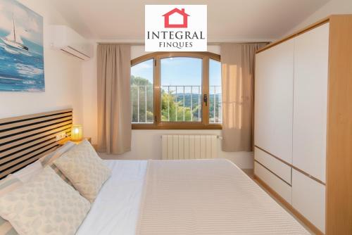 a white bedroom with a bed and a window at Casa Serena in Vall-Llobrega