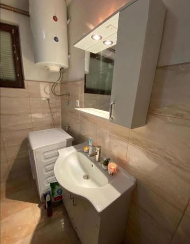 a bathroom with a white sink and a mirror at Apartmani Benjamin in Tuzla