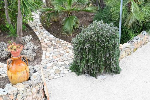 a stone walkway with a vase with flowers in a garden at Casa Macchiosa in Torre Canne