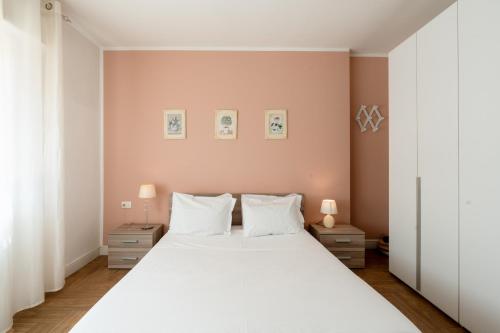 a bedroom with a large white bed with two lamps at Gold Apartment in Ferrara