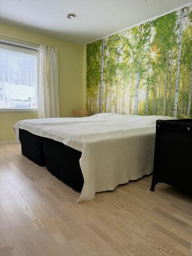 a bedroom with a large bed with a mural of trees at Red House at Kuusitie in Kittilä
