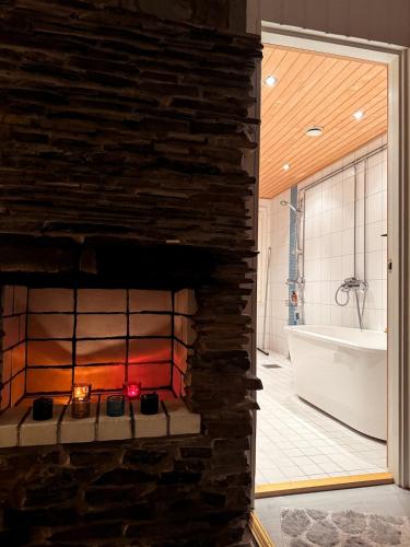 a stone fireplace in a bathroom with a bath tub at Red House at Kuusitie in Kittilä