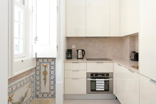 a white kitchen with white cabinets and a window at LSA Baixa Chiado by Numa in Lisbon