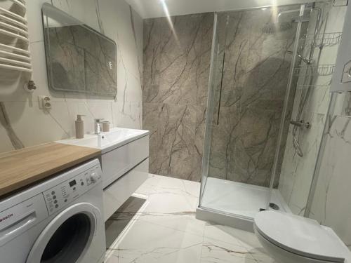 a bathroom with a shower and a washing machine at Apartament Świder - przytulny, cicha okolica in Otwock