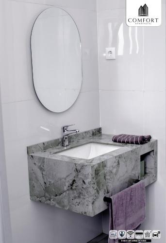 a bathroom with a marble sink and a mirror at Comfort Aparthotel in Chimoio