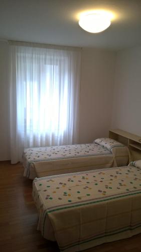 three beds in a room with a window at Appartamenti Fabila in Castello Tesino