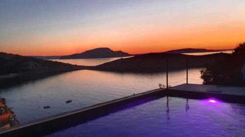 a swimming pool with a view of a lake at sunset at House Vissum by Villas Guide in Lukovo