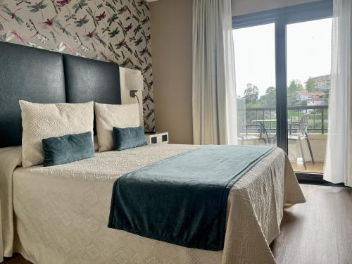 ein Schlafzimmer mit Kingsize-Bett und Balkon in der Unterkunft Hotel Boutique Aquaria Caneliñas in Portonovo