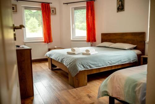 a bedroom with two beds and two windows with red curtains at Pensiunea Rozelor Stațiunea Climaterică Sâmbăta in Sâmbăta de Sus